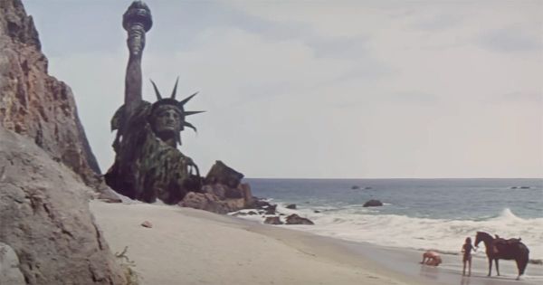 Ruined Statue of Liberty on a deserted beach from "Planet of the Apes," symbolizing the collapse of civilization and the passage of time.