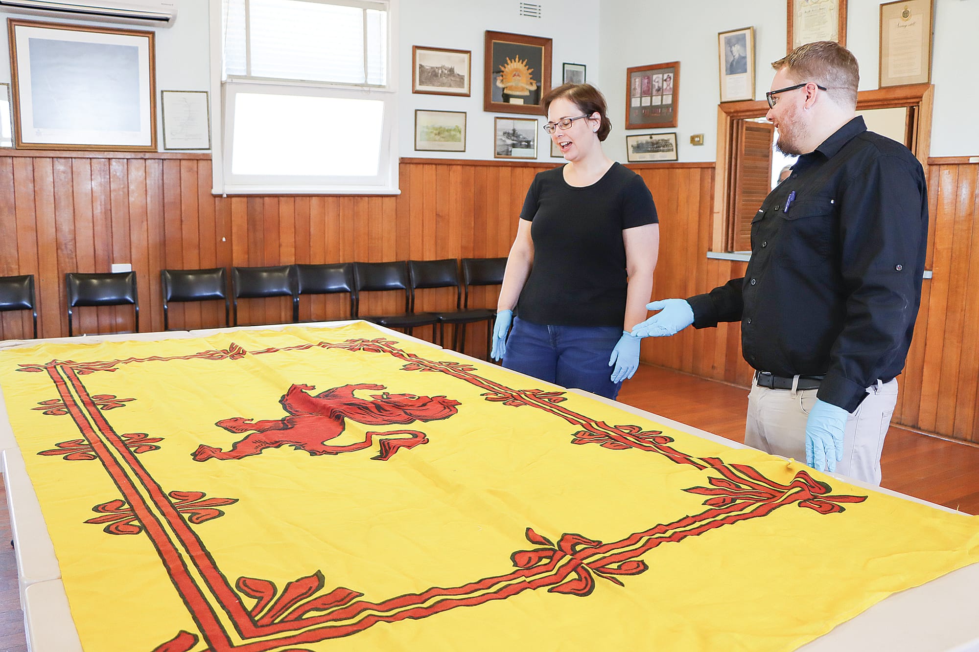 Amanda New and Bryce Abraham of the Australian War Memorial inspect a Royal Banner of Scotland that features in the Paterson collection. A03_0925