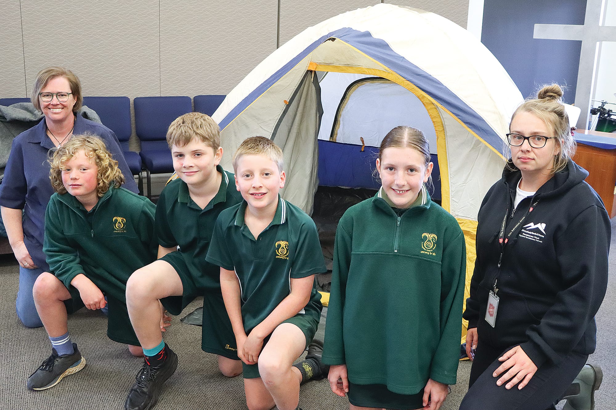 Corps Officer Amanda Hart, Leongatha Primary School students Olly, Jhett, Ben and Nicola, and homelessness program team member Hayley with a tent illustrating how some people live due to the cost of living and other circumstances. A03_3225
