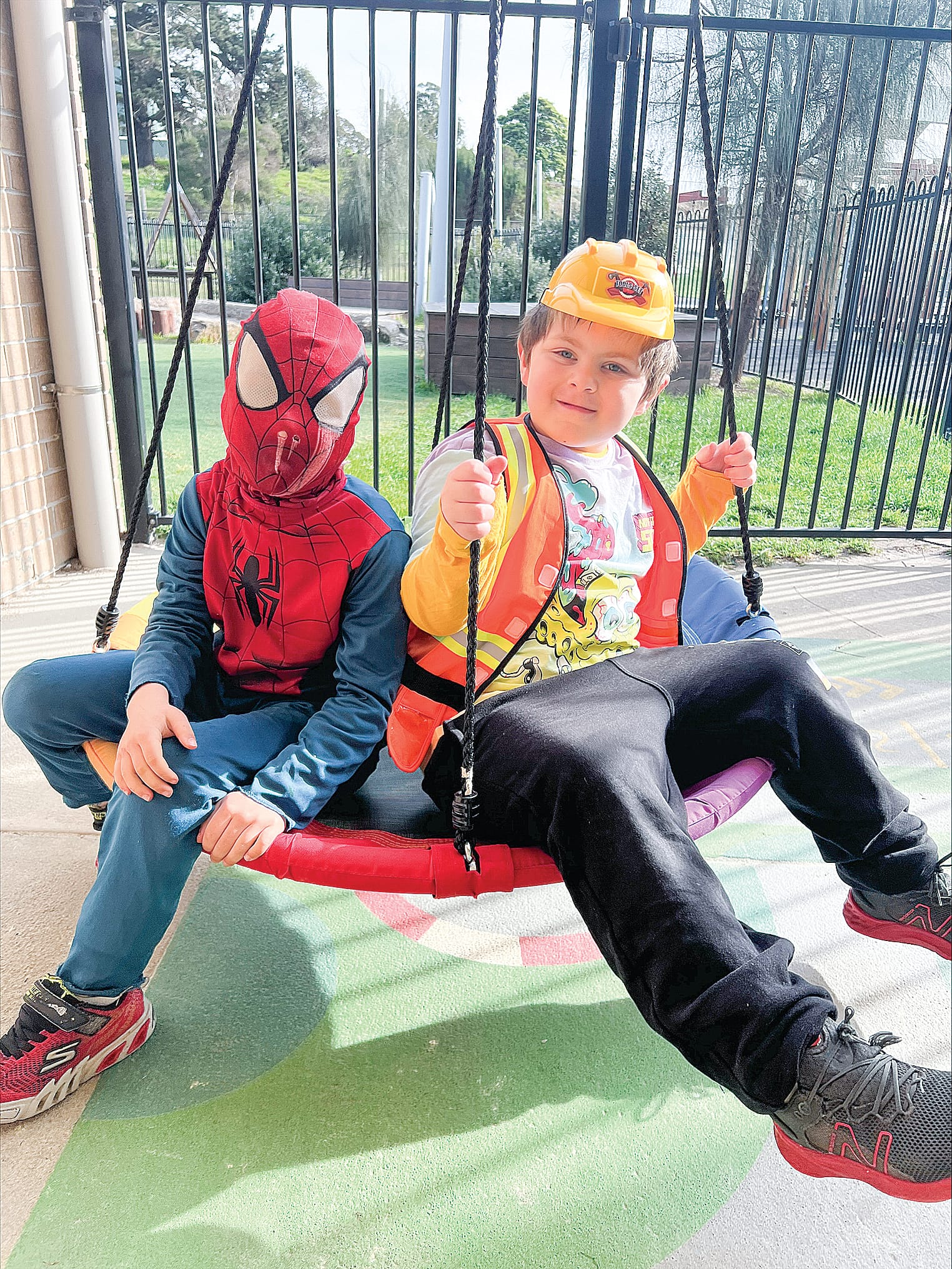 Spiderman Rhys and Bob the Builder Dwayne on the swing together. 