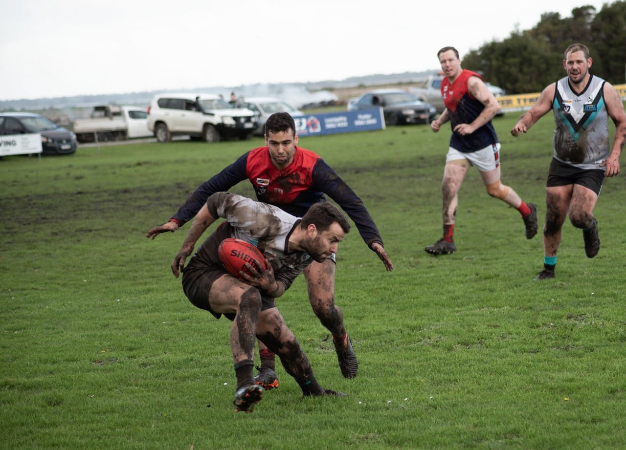 Josh Toner braces for the tackle as both sides battle it out in muddy conditions.