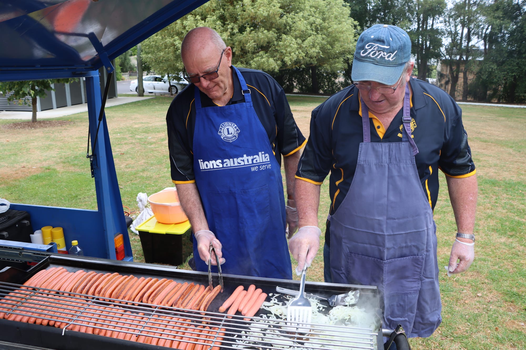 Geoff Wood and Gil Twite of Korumburra Lions Club ensure those celebrating Australia Day in the town ensure the Aussie tradition of a snag in bread.