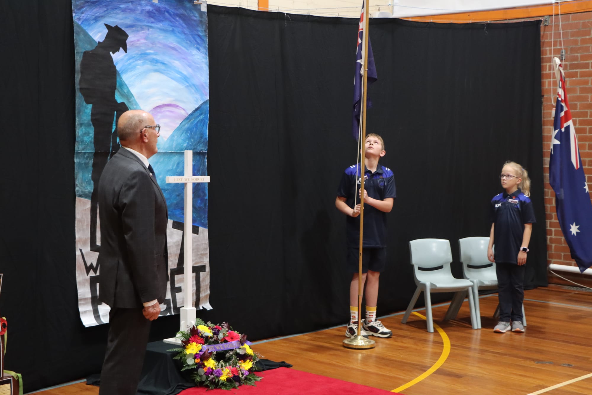 Korumburra Primary School vice captains Thomas Moon and Lara Pickering take part in Anzac commemorations while local RSL president David Jackson looks on.

