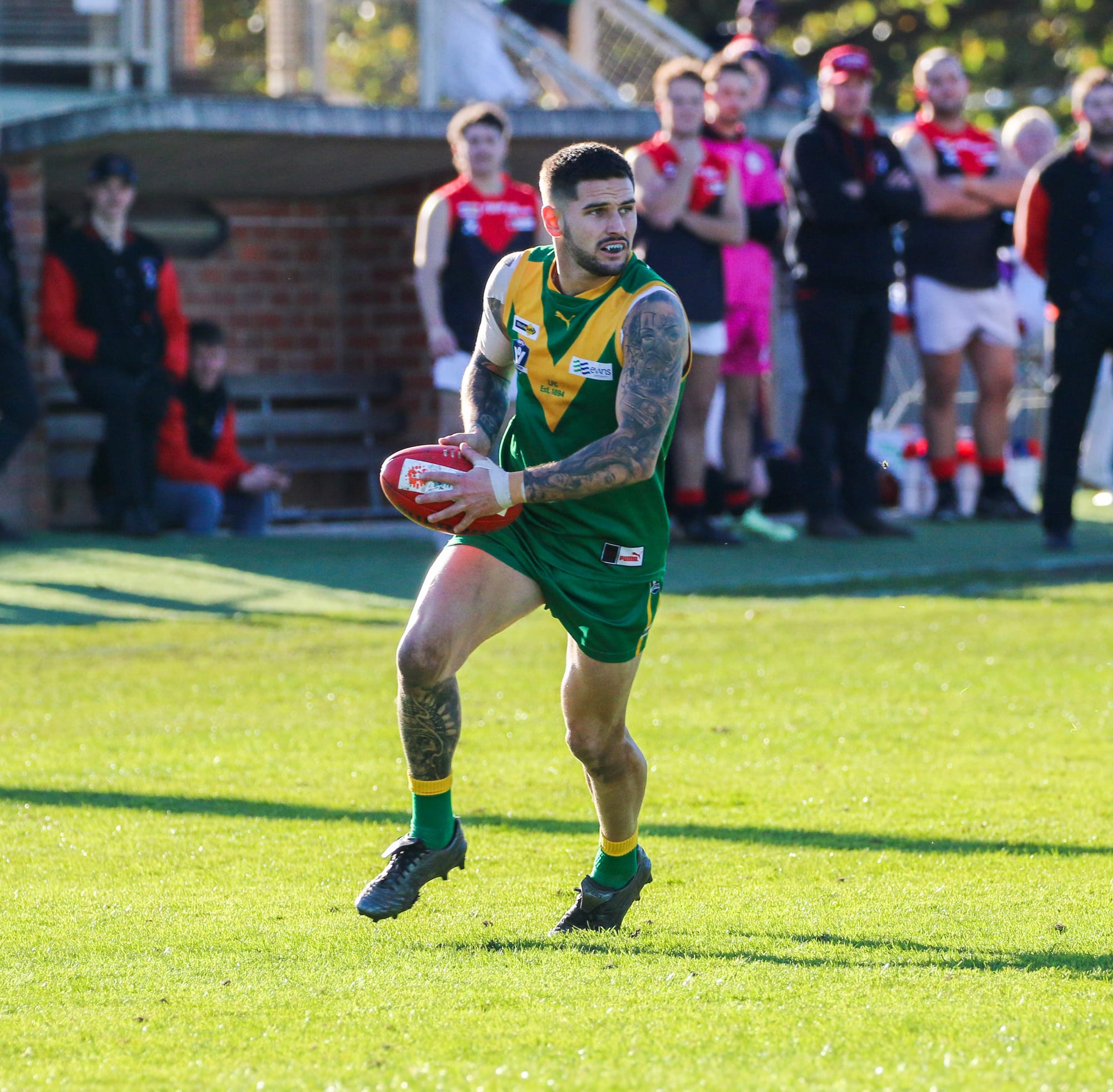 Tallin Brill takes off with the ball and kicks towards goals as Warragul spectators look on. Ob11_2623