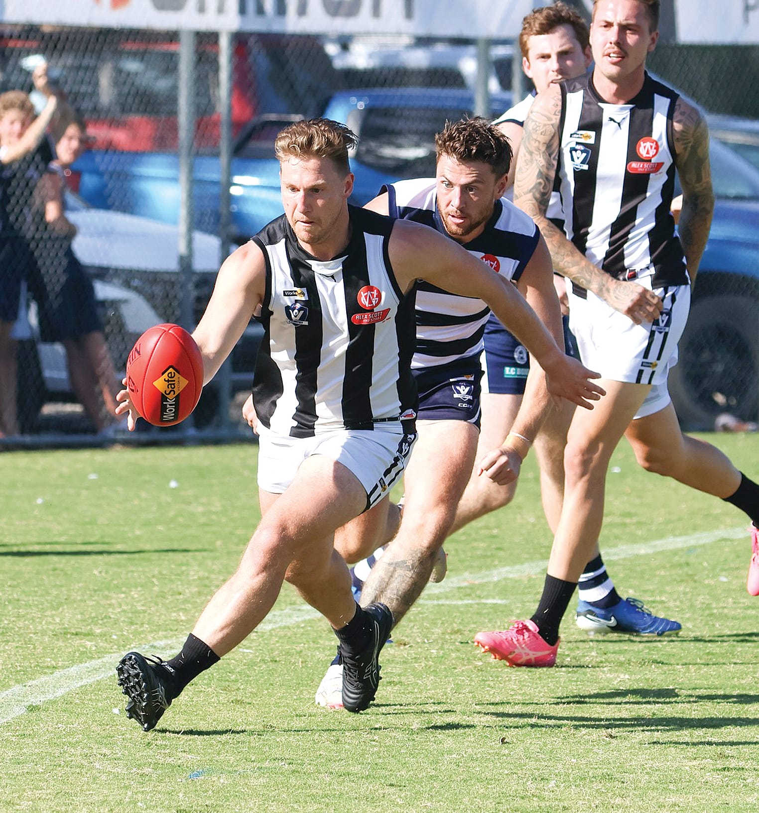 Blake Carew tracks the ball along the boundary line under extreme Nar Nar Goon pressure. 