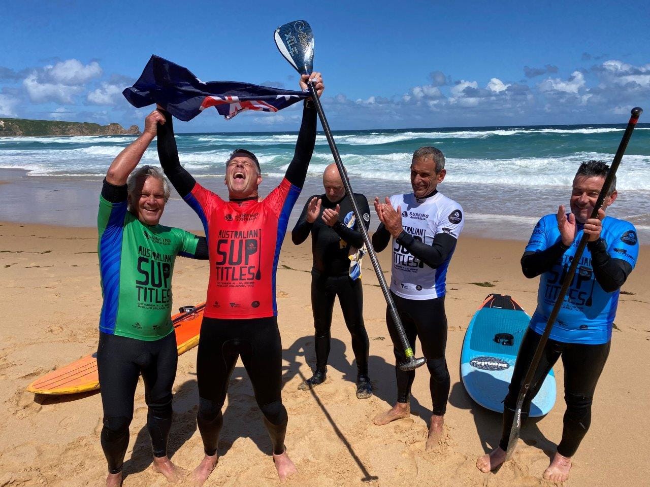 Andrew Cassidy hears the official announcement that he has won the Australian Under 50s SUP surfing title at Woolamai Beach on Saturday, sharing the moment with, from left, John Takle, Michael Jenkins, Crawford Olney and Damien Quinlan after the final.