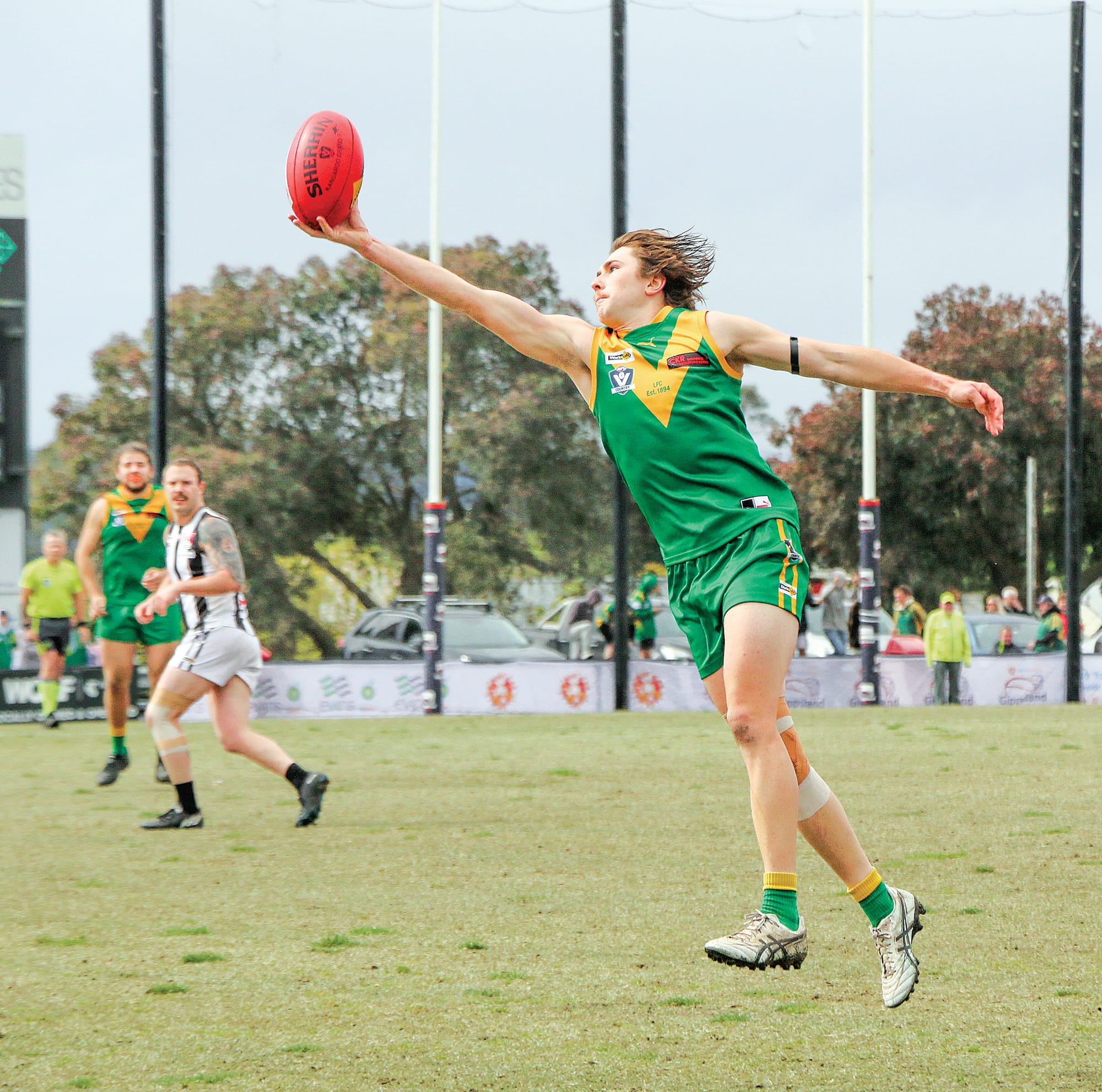 Mason McGannon balances the ball one handed as he makes a marking attempt in the Resreves grand final.
