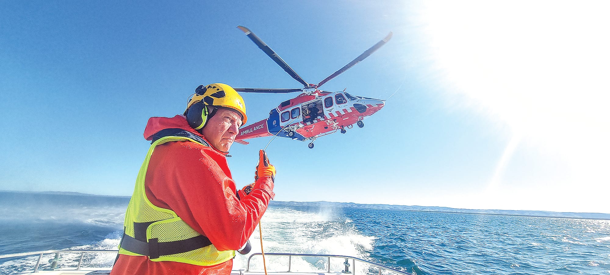 A Port Welshpool Coast Guard crew decked out in full wet weather gear, crash helmet, ear muff, and safety glasses handles the&nbsp;Victorian Air Ambulance Helimed rescue chopper&nbsp;overhead&nbsp;that has dropped a fender line to the deck. Photo Jonathon Stevenson