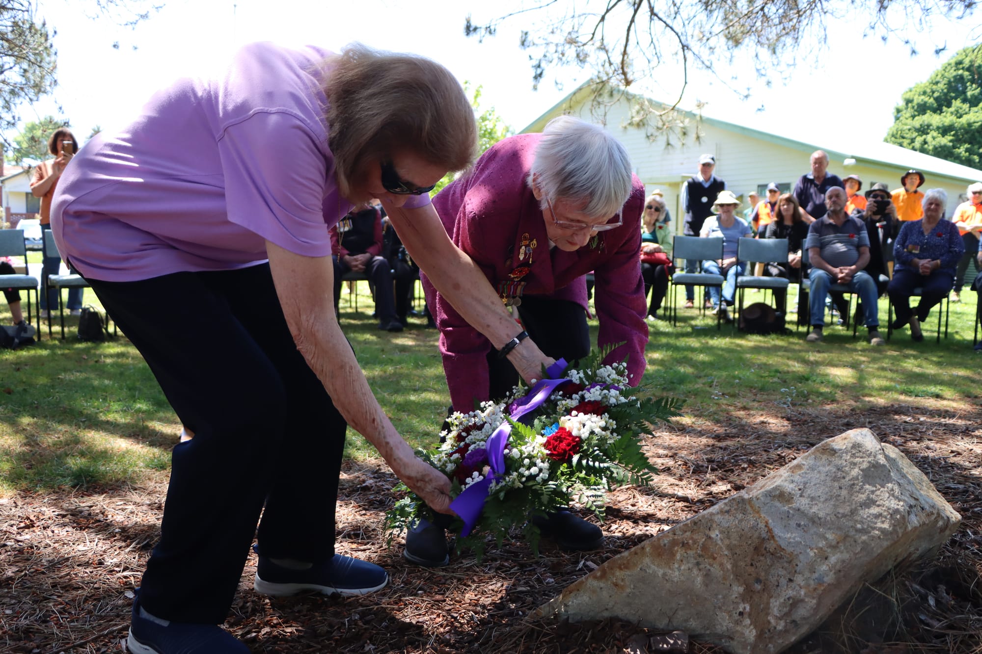 Mary Fields and Avis Tilley place a wreath near the Lone Pine plaque. 