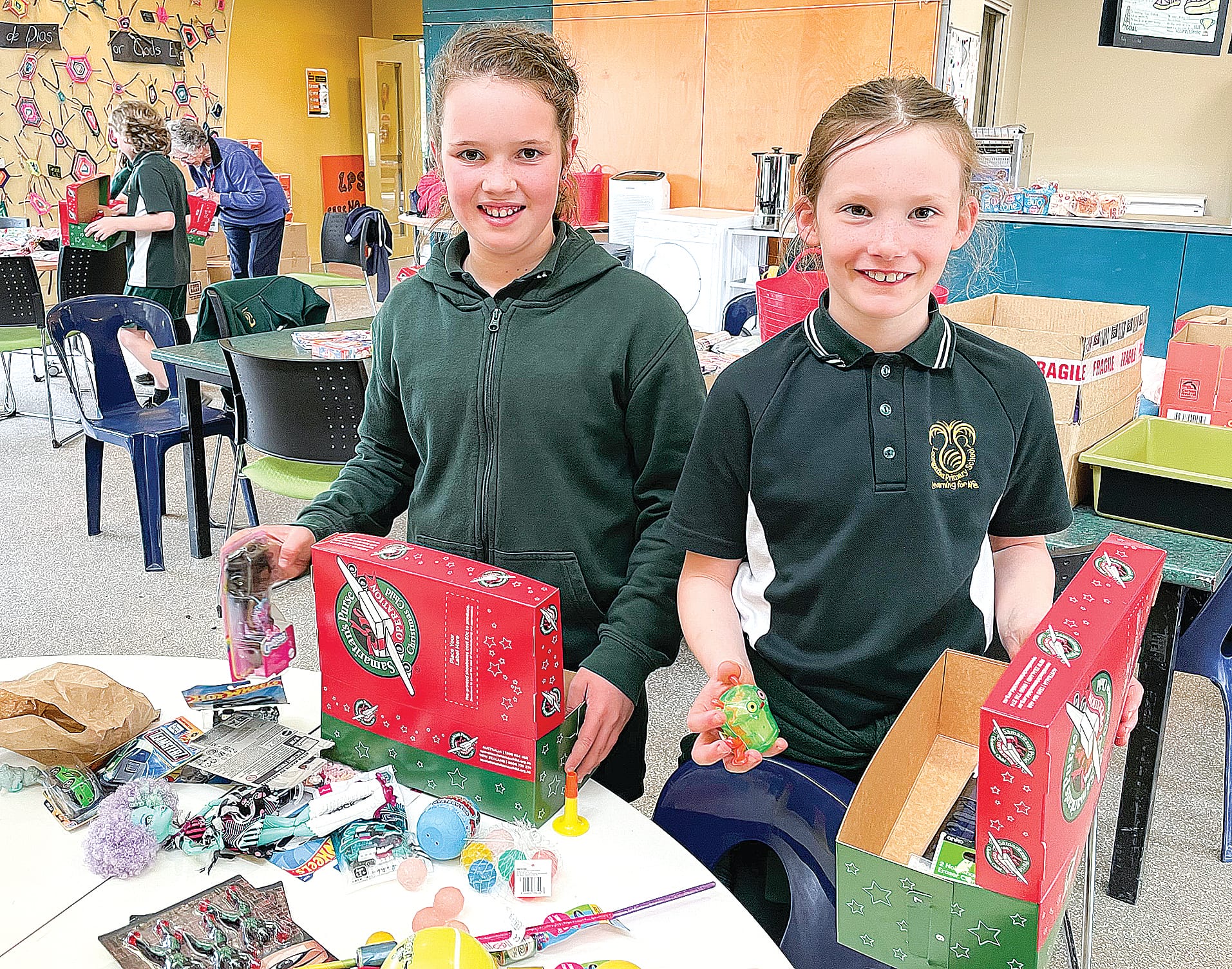 Grade 5 student Remy and Lexi from grade 3 pitch in to fill shoeboxes for Operation Christmas Child.