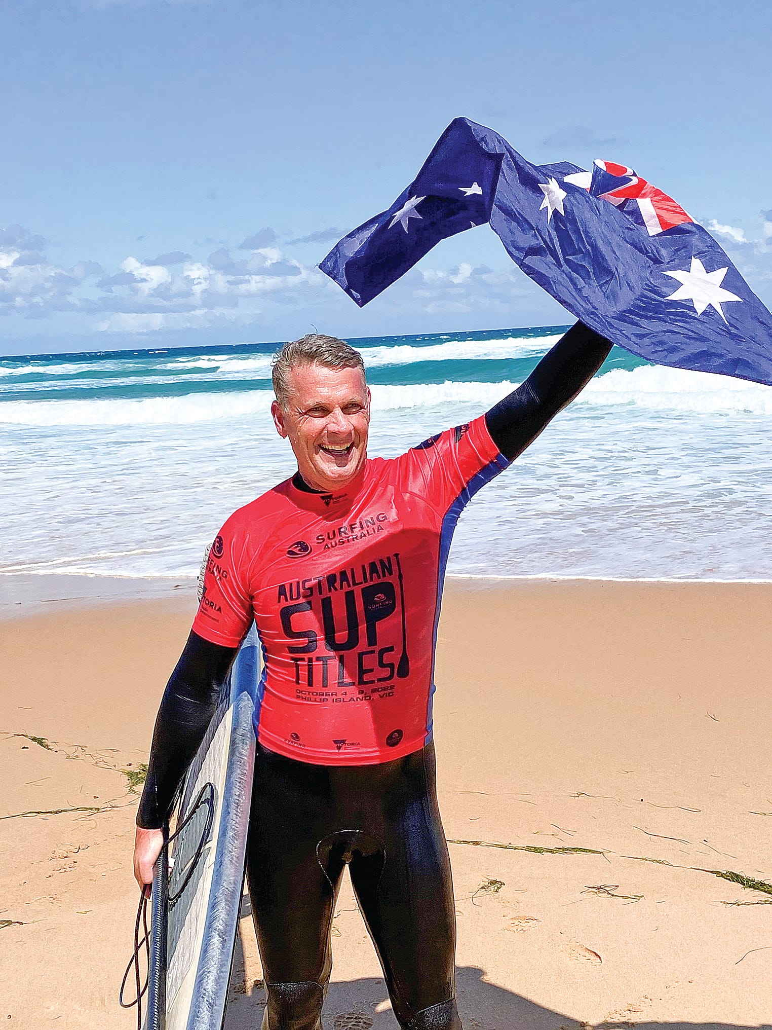 A delighted Andrew Cassidy salutes the crowd as his name is read out as winner of the Over 50s Australian SUP title.