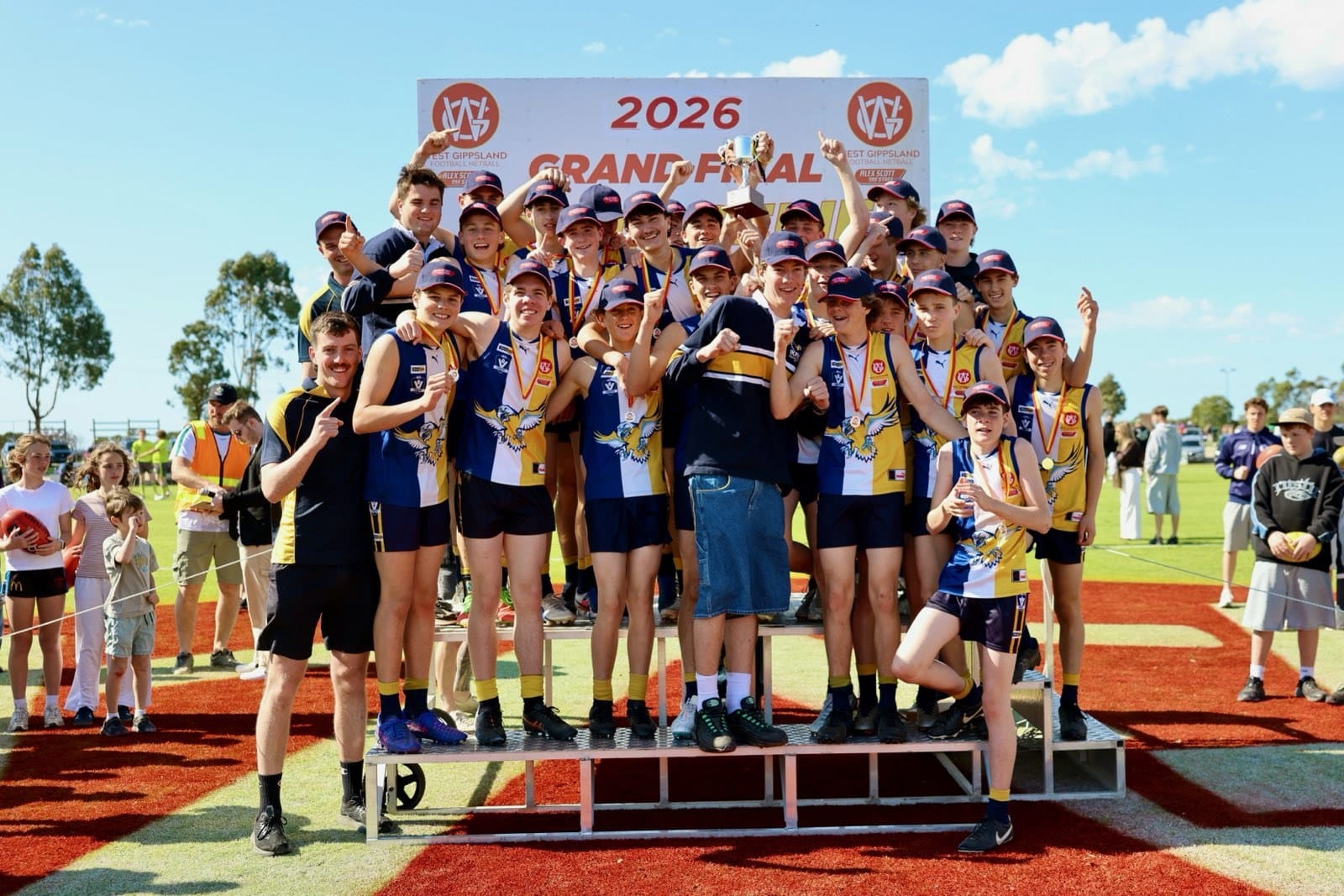 The Inverloch-Kongwak fourths celebrate on the podium with the premiership cup