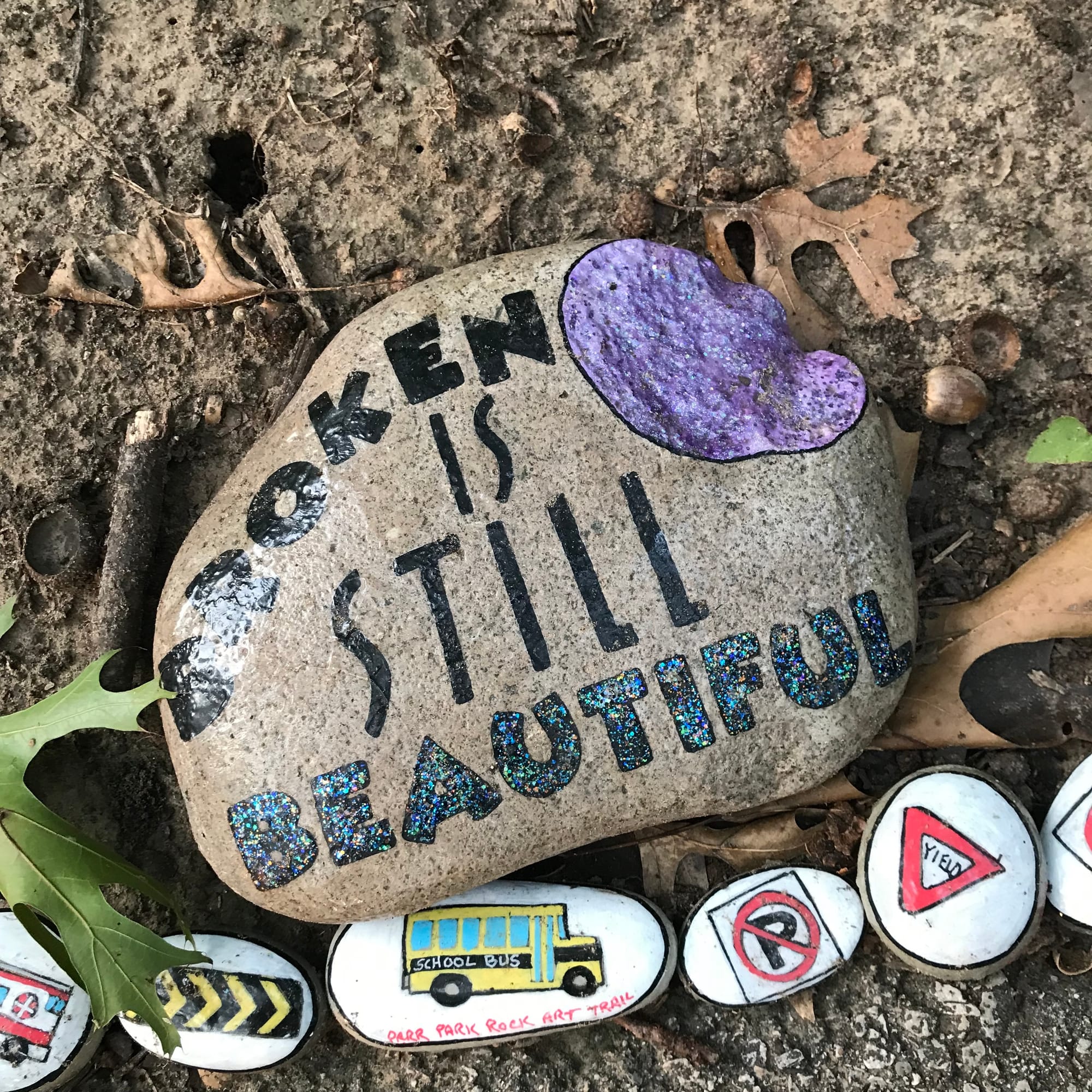 A rock at the Parr Park Rock Art Trail painted with "Broken is still beautiful”