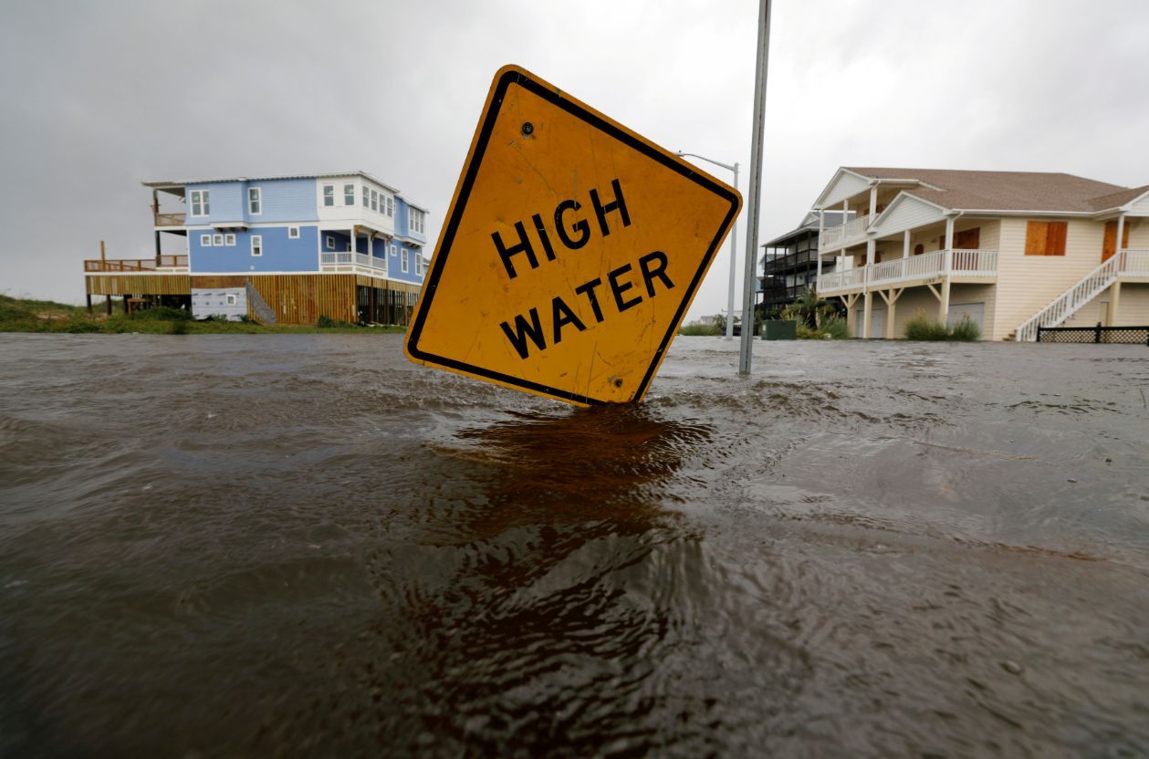 Flood-waters-lap-at-a-high-water-warning-sign-that-was-partially-pushed-over-by-Hurricane-Florence-on-Oak-Island,-North-Carolina,-on-September-15,-2018.-(REUTERS/Jonathan-Drake-TPX-IMAGES-OF-THE-DAY)