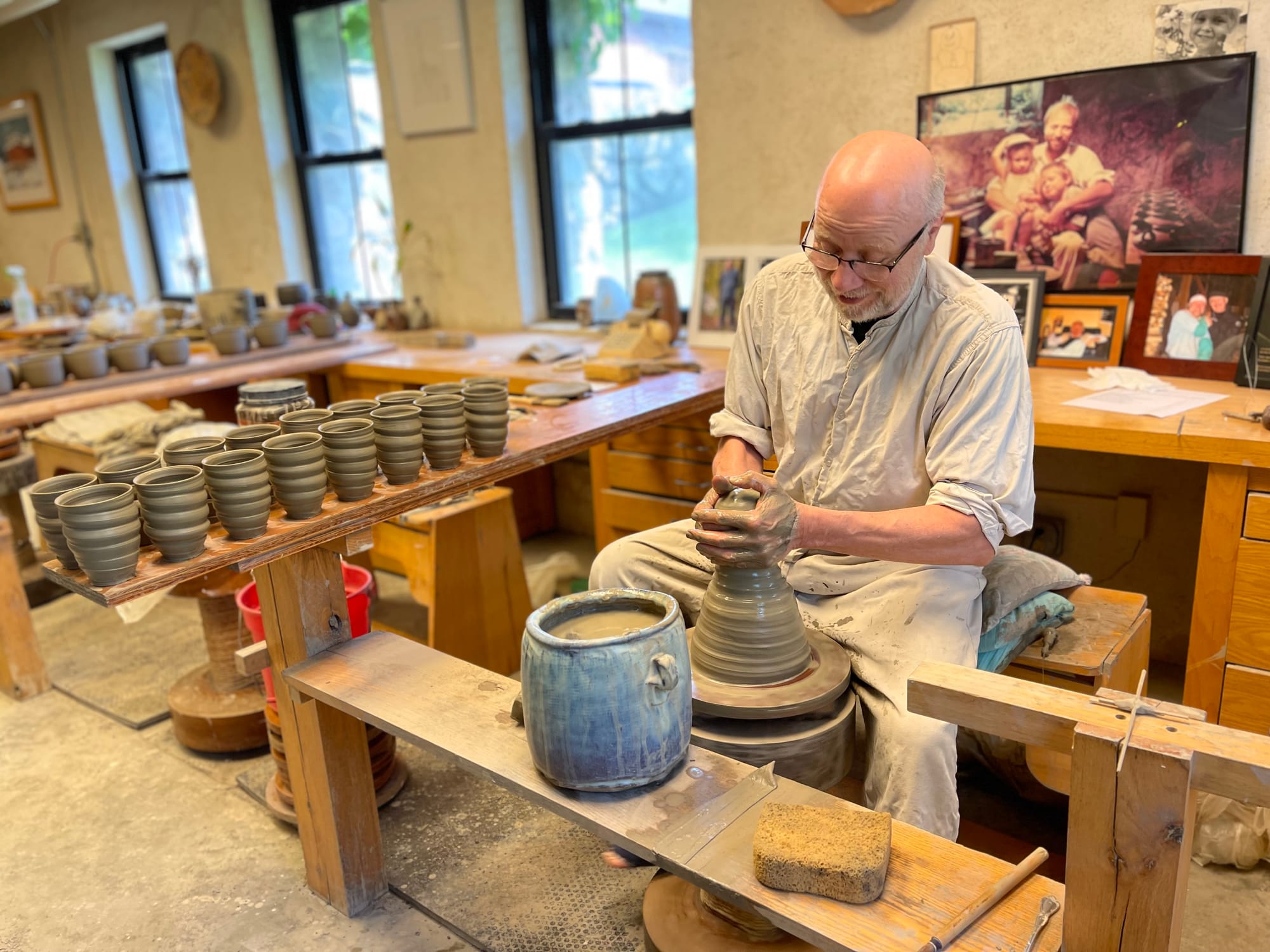 Man makes pottery at a potters wheel in a studio.