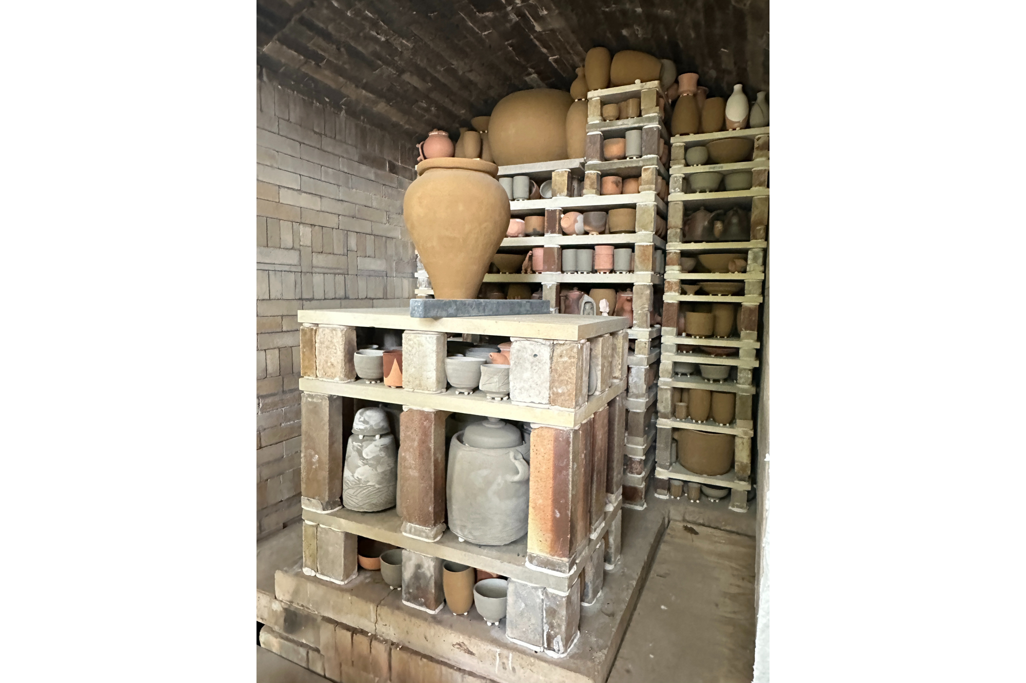 Pottery is stacked neatly in a large kiln as it waits to be fired.