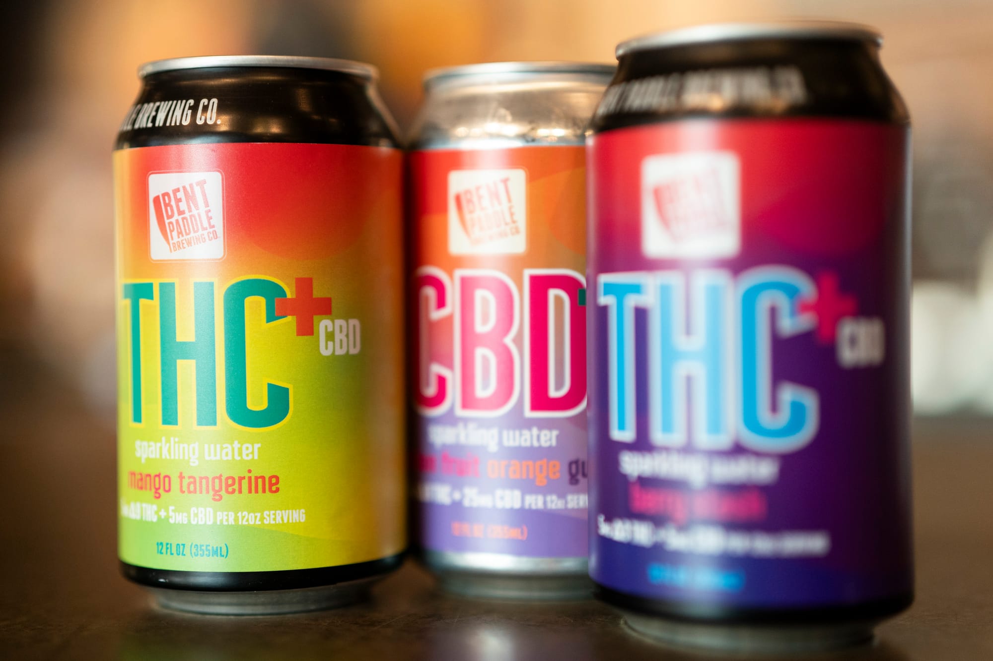 Three cans sit on a bar.