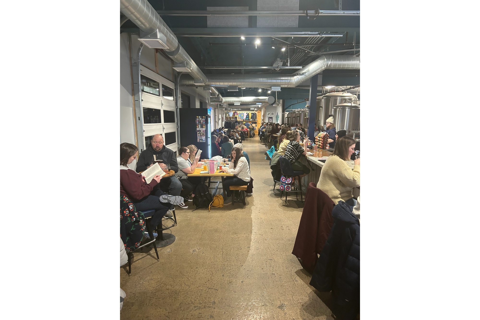 People read books in a brewery as part of a silent book club. All the seats pictured are full.