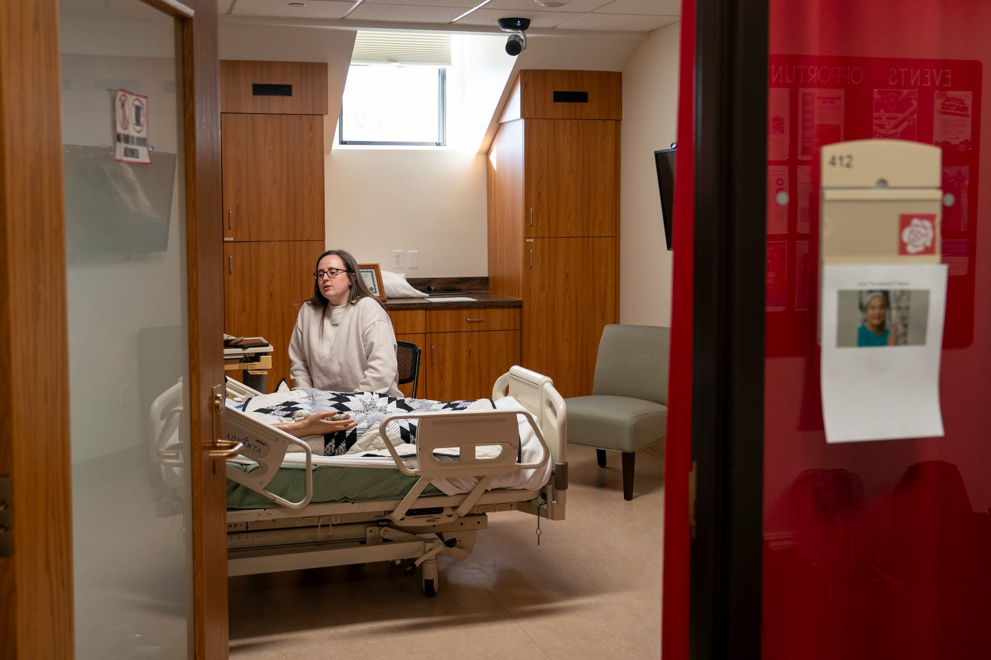 A person talks to a mannequin in a hospital bed during a training exercise for nursing students. 