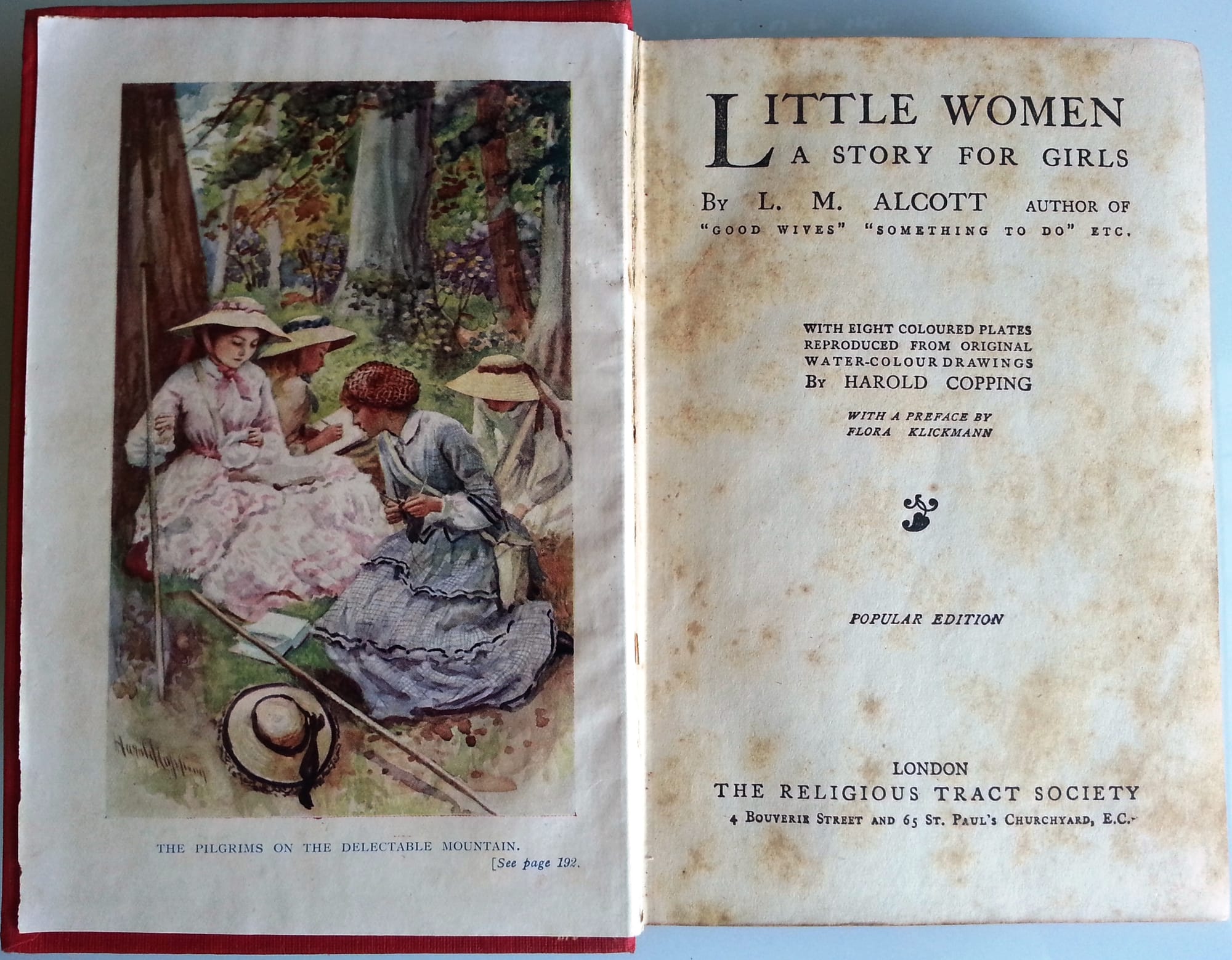 An edition of Louisa May Alcott's book "Little Women" is open to the title page and includes an illustration of the March sisters. 