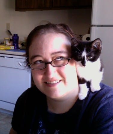 Rooley, a black and white kitten, sits on my shoulder in my apartment in Sacramento.