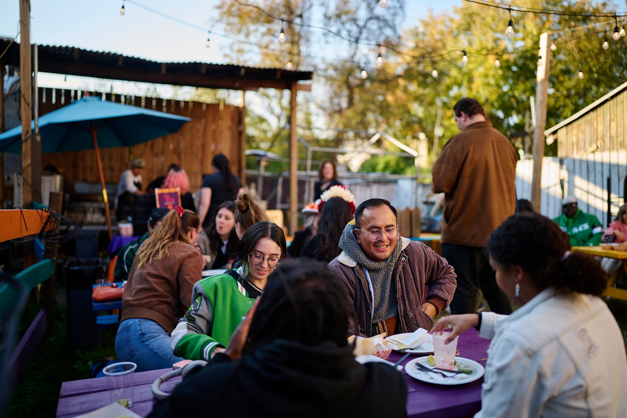 Friends share a meal at a colorful picnic table during Día de los Muertos celebration