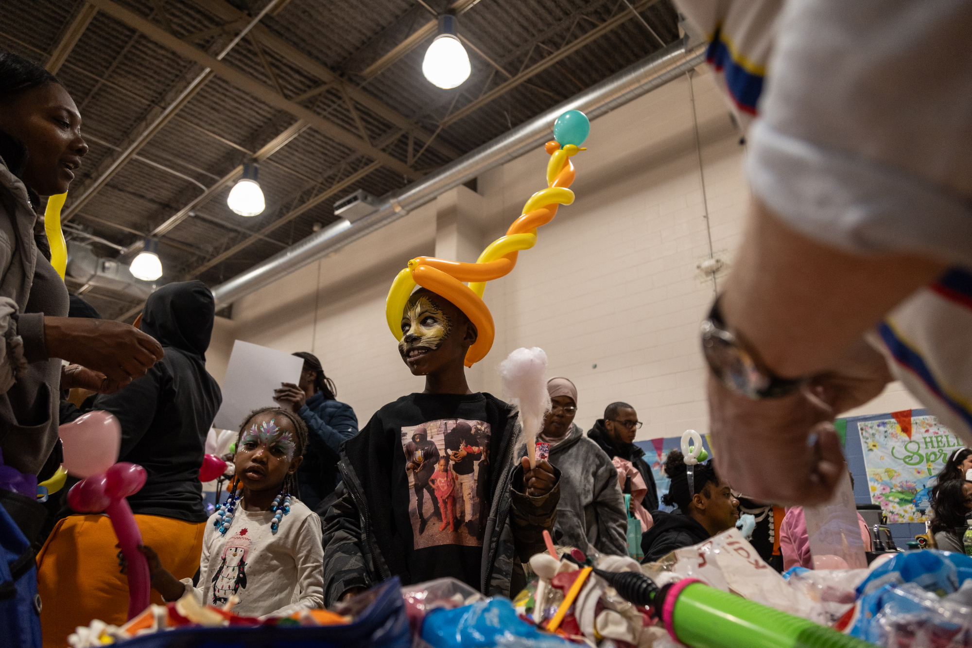 Child with lion face paint and balloon hat at Heitzman Spring Festival