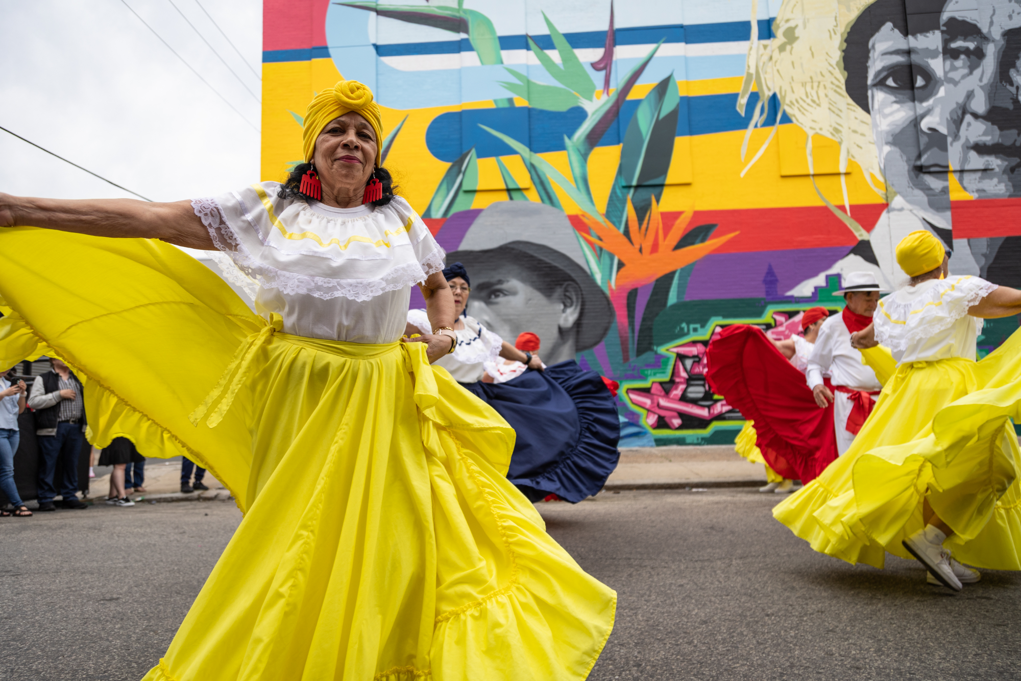 Bomba dancer in yellow skirt performs at Norris Square mural unveiling