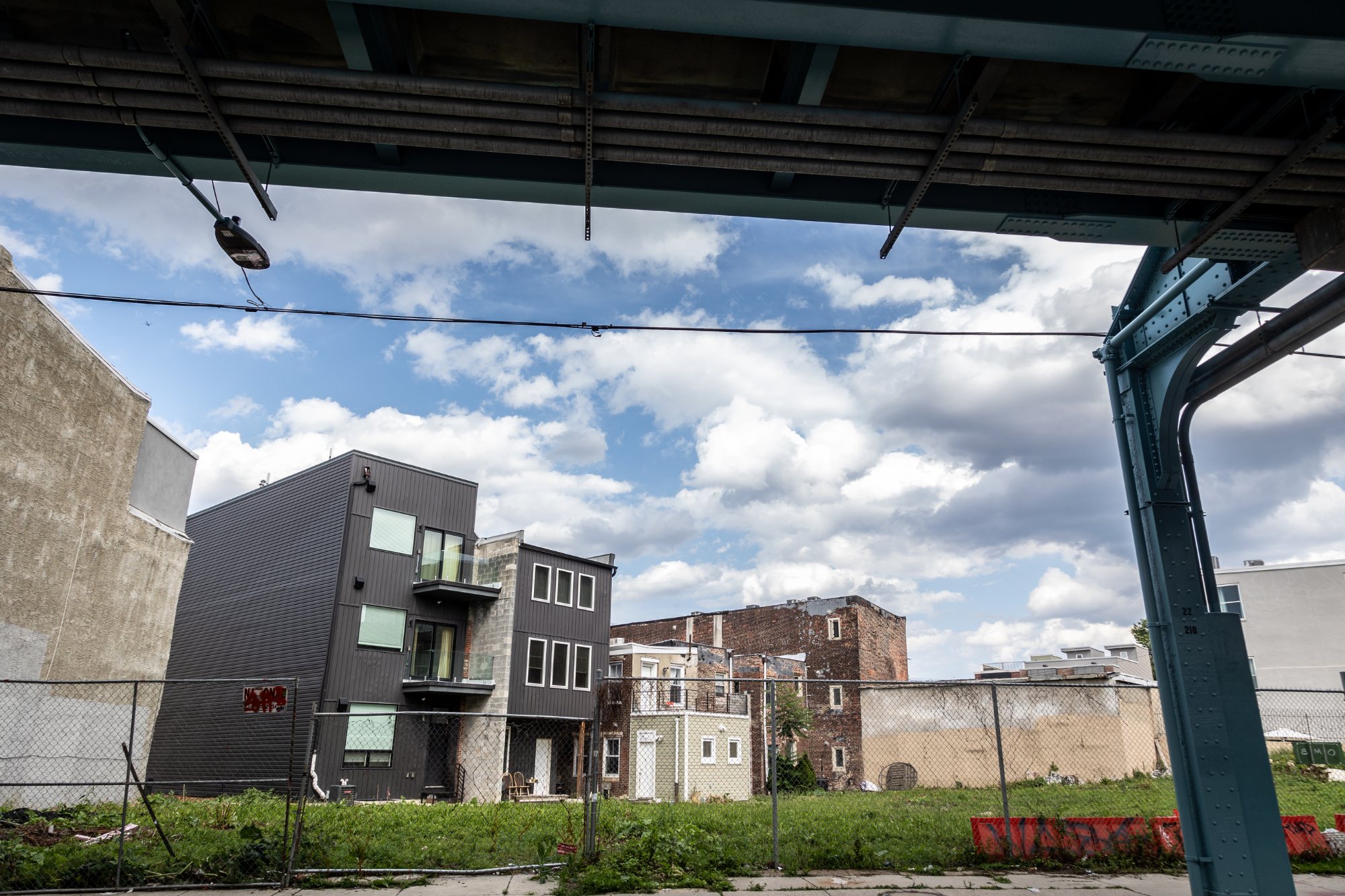 New apartment building beside existing rowhomes under the el in Norris Square