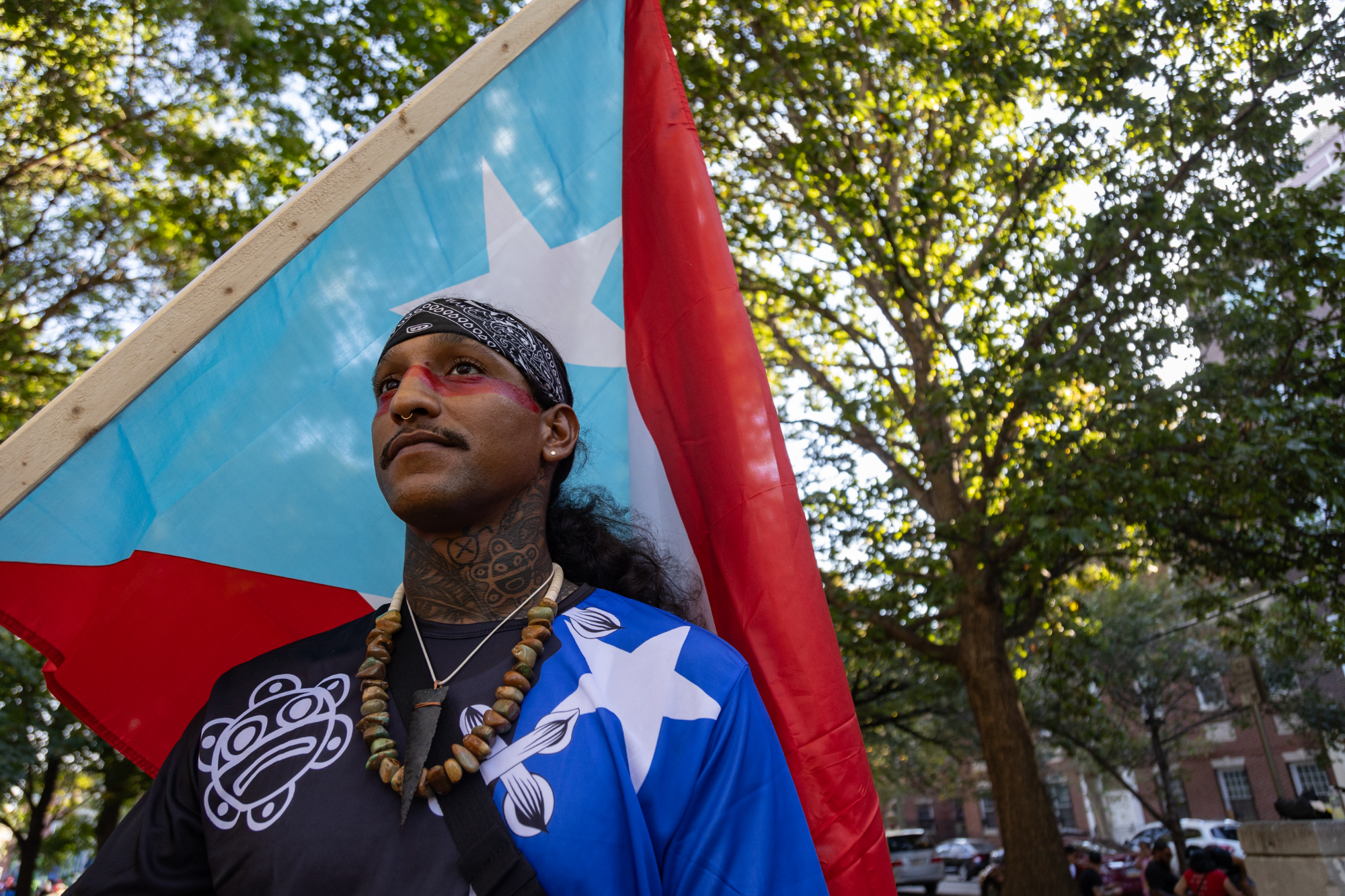 Miguel holds light blue Puerto Rican flag at Fairhill Square Park