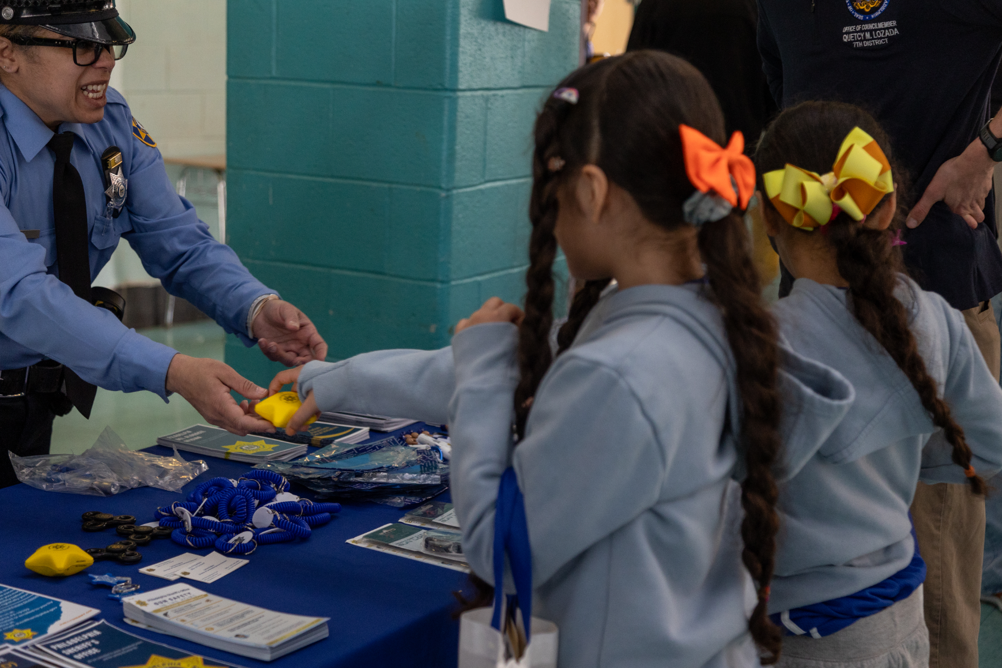 Police officer hands toy to children at Councilmember Quetcy Lozada's resource fair