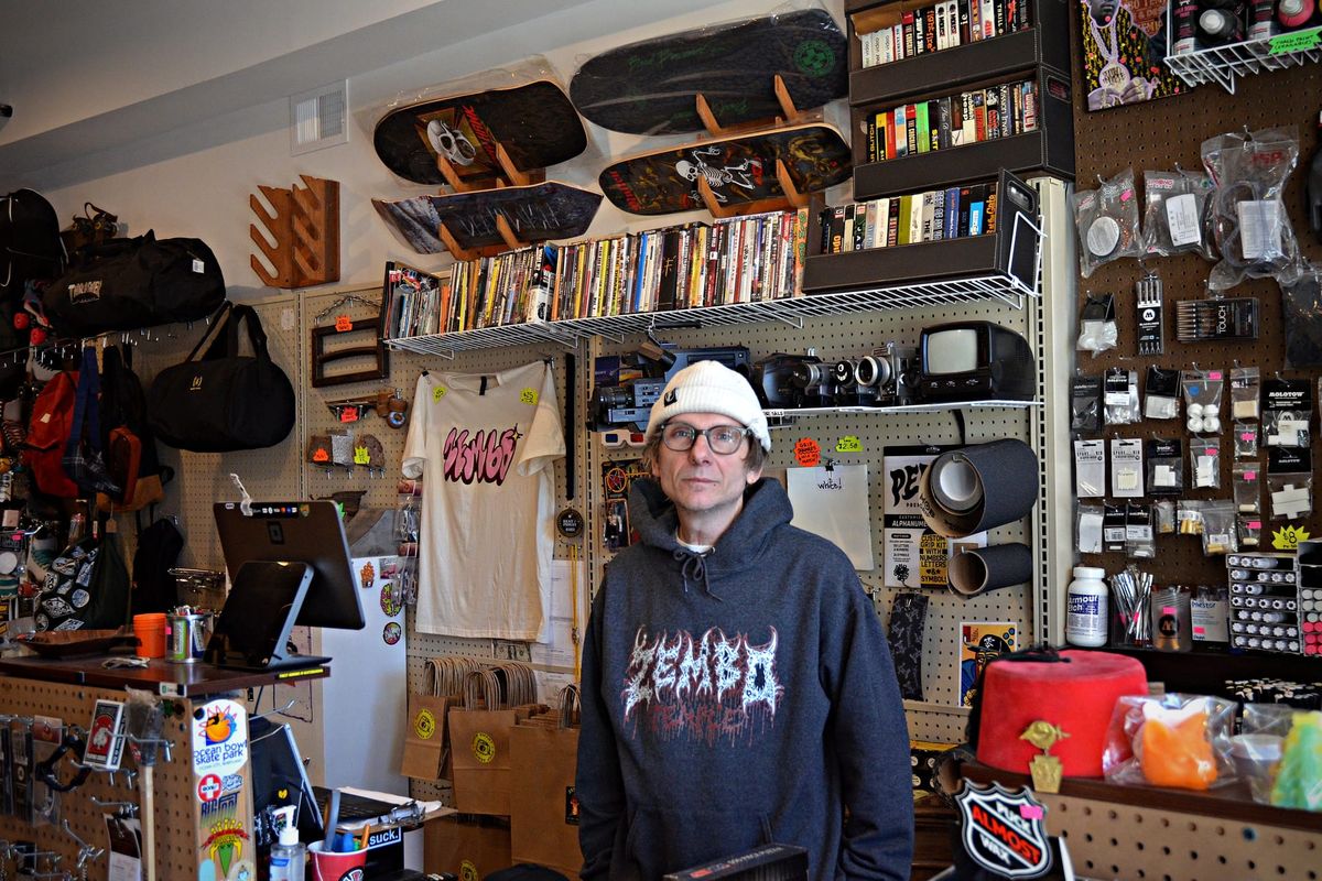 Chad Dravk stands behind the counter of his skate shop, surrounded by skateboards, art supplies, vintage cameras and clothing.