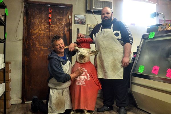 Mike Crouse, left, and Jeff Czerw at Czerw’s Kielbasa in Port Richmond, alongside the pig statue that traveled to John Czerw’s funeral.