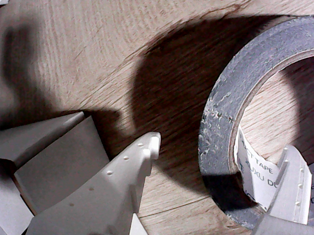 A fingertip reaches into the tape core before the successful grasp