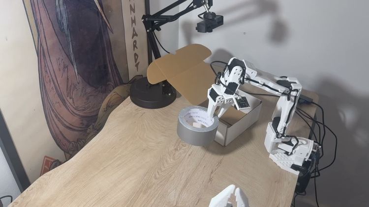 SO-101 robot carrying duct tape toward a cardboard box