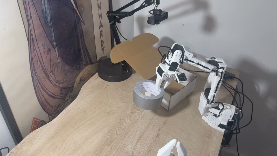 SO-101 robot carrying duct tape toward a cardboard box