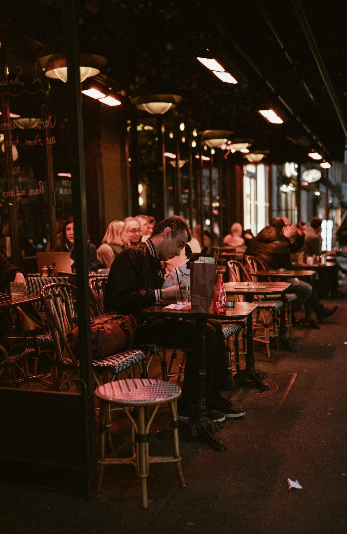 Man sitting alone at a busy café surrounded by people