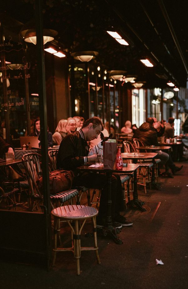 Man sitting alone at a busy café surrounded by people