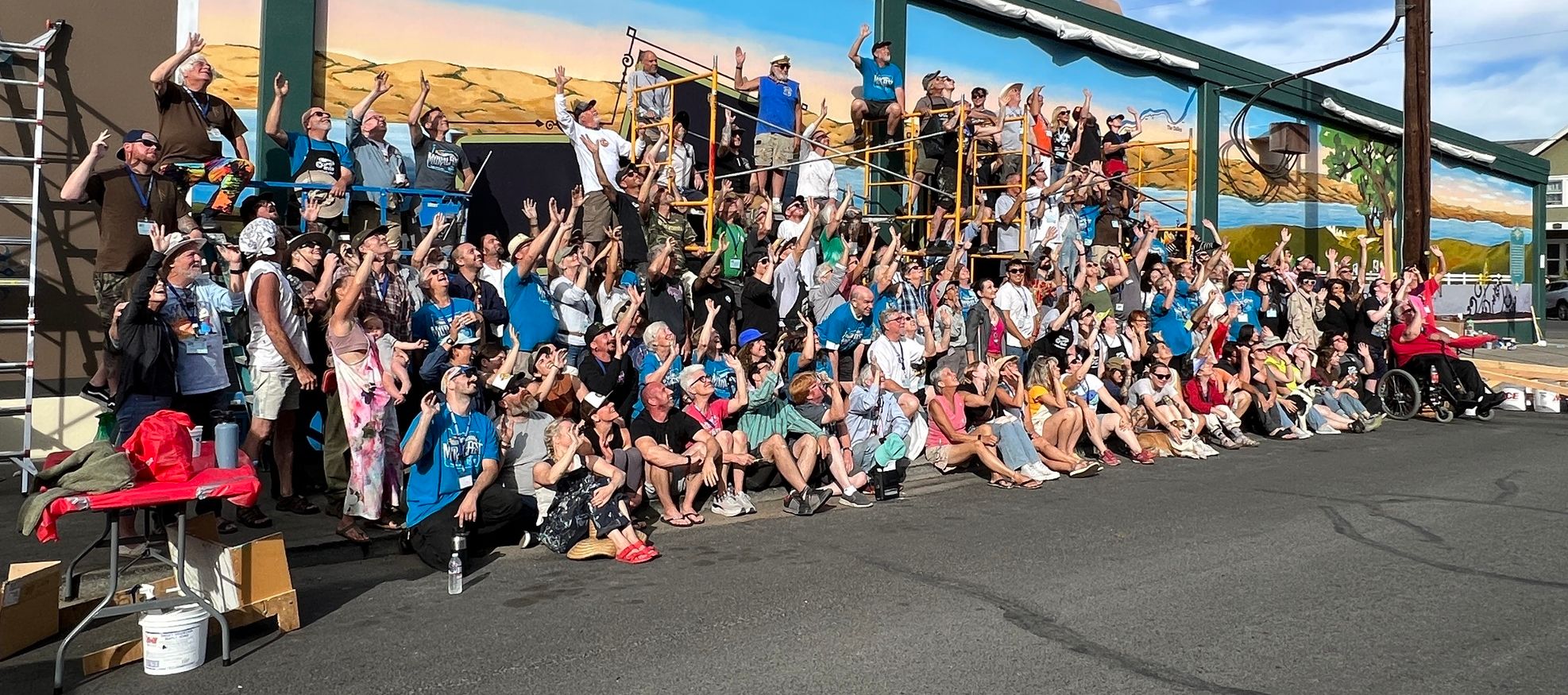 Group of people in front of a large painted mural.