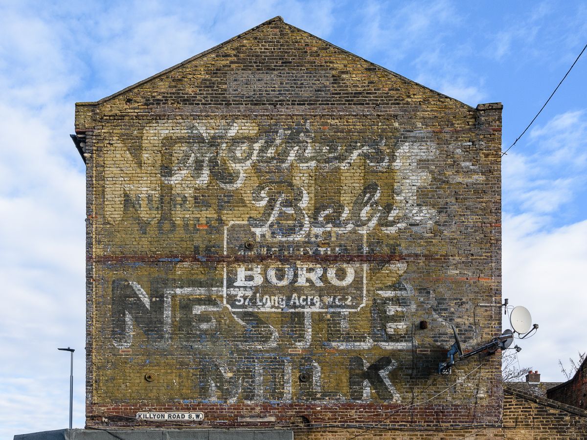 Multiple layers of painted advertising fading on a brick wall.