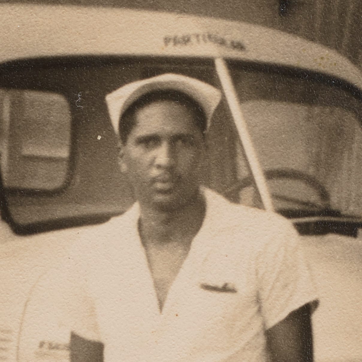 Photo cropped to give a head and chest image of a man in an open-necked shirt and hat.