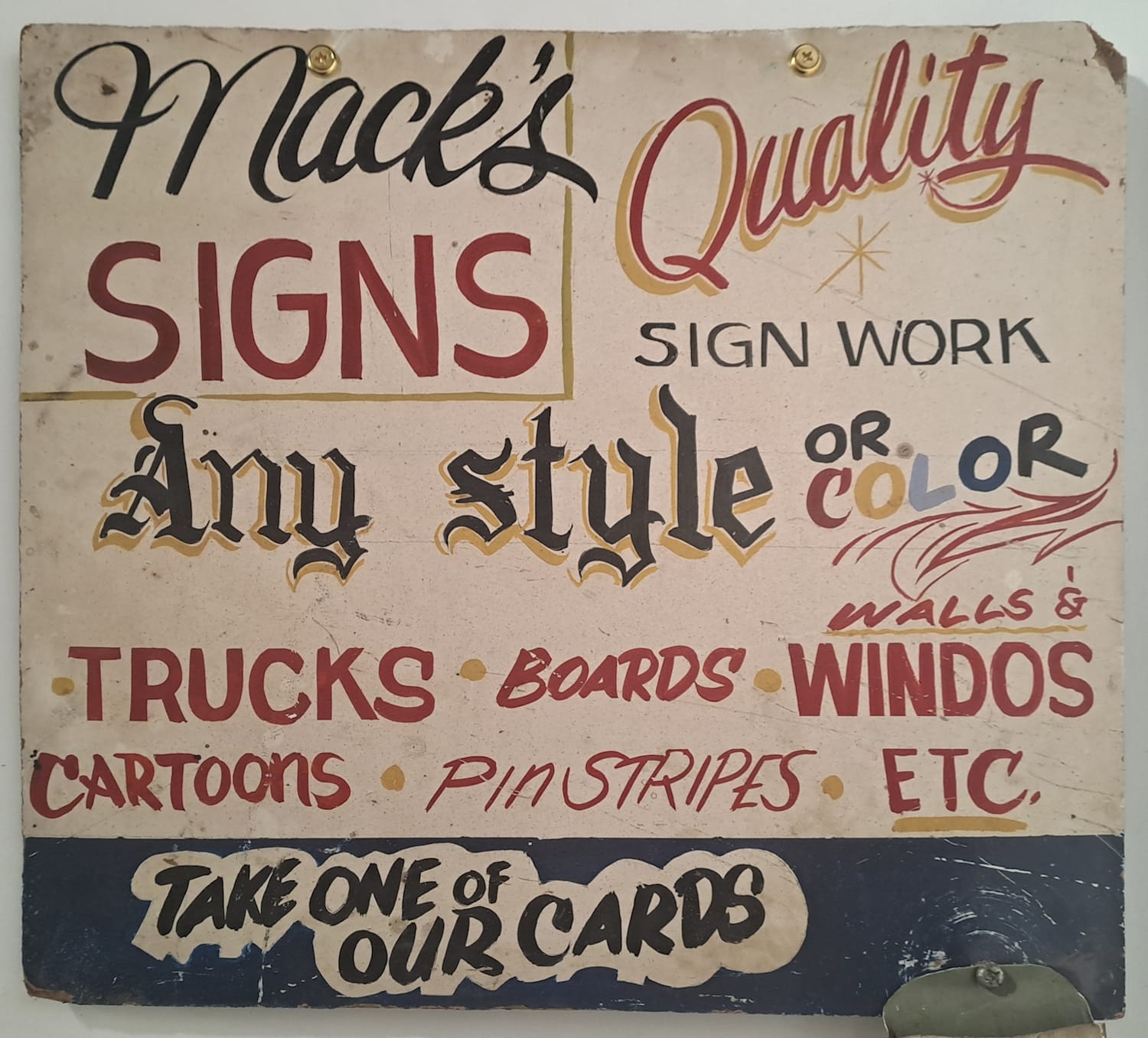 Square hand-painted sign advertising Mack's Signs. It is poorly laid out and lettered in a riot of different styles, but makes the claim of "Quality Sign Work" in and amongst it all.