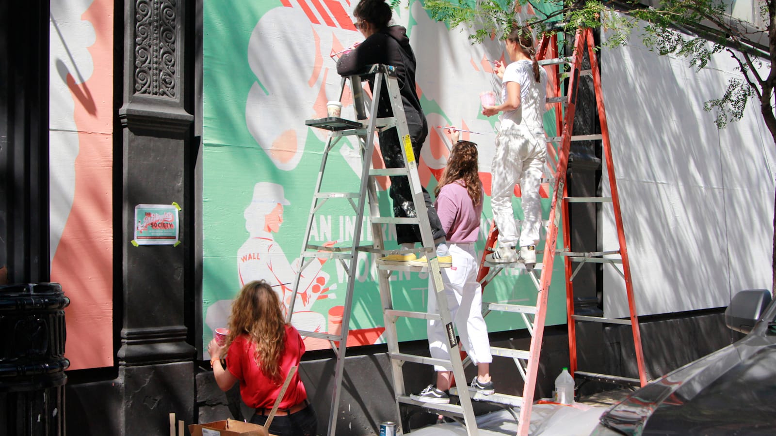 Four women painting a mural.