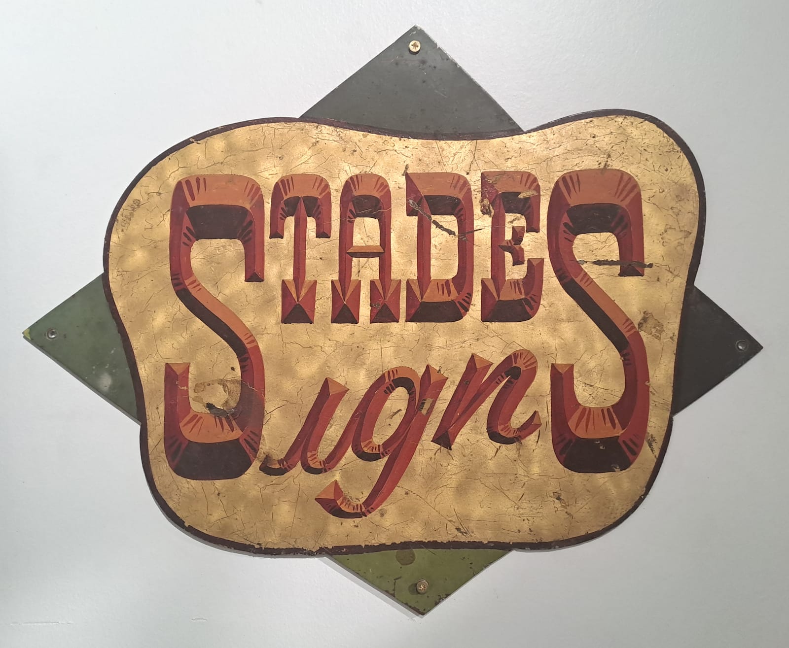 Wild West style convex lettering in red for Stades Signs set on a panel with an engine-turned gold leaf background.