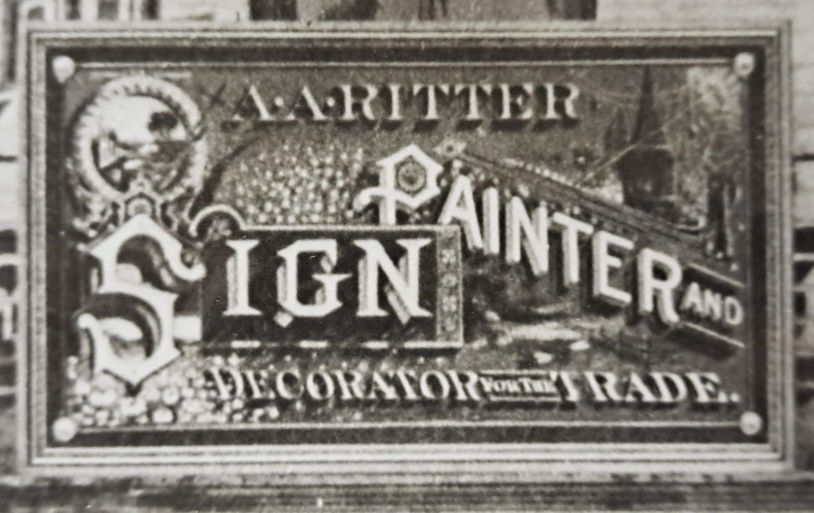 Detail of one of the signs from the picture above. It has a variety of ornate lettering styles, blended with pictorials and decorative elements, and reads "A.A. Ritter, Sign Painting and Decorator for the Trade".