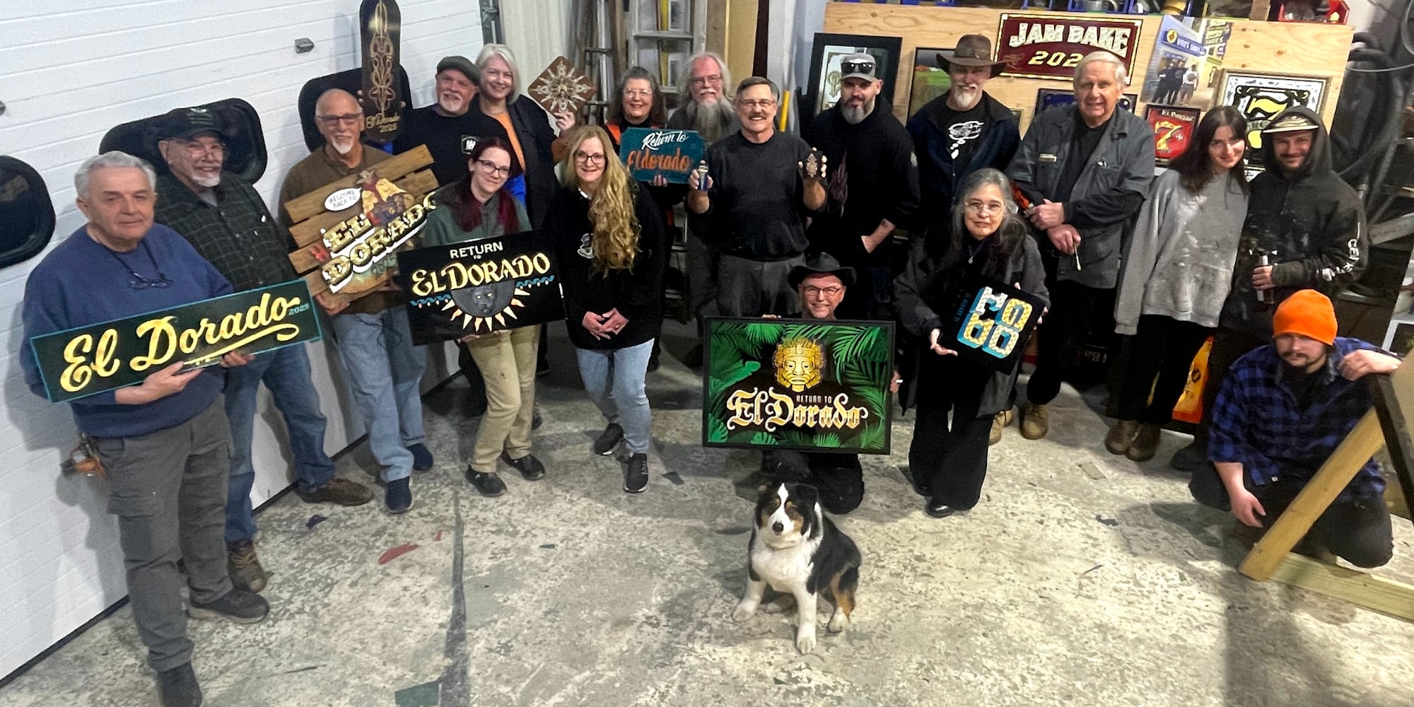 Group photo with men and women facing the camera and holsing painted and gilded panels lettered with "El Dorado".