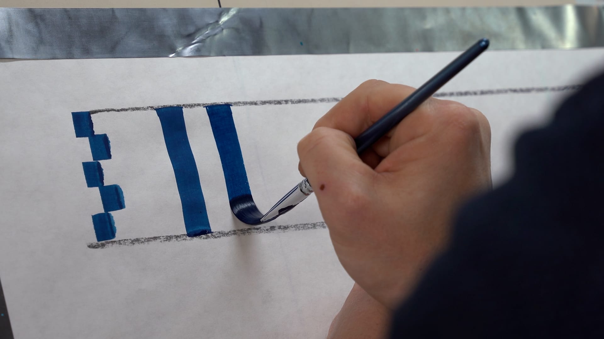 Photo of a hand painting a vertical blue line between two horizontal guidelines. This is the second such stroke, and the horizontal lines are set five brushstroke widths apart.