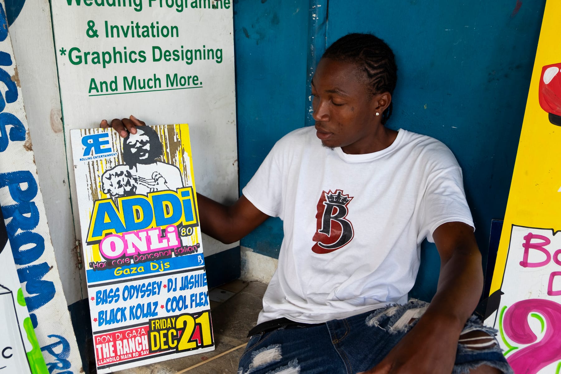 Man sat holding a sign to his side that has a picture of a person on it and then lettering that says "ADDi ONLi, Gaza DJs" with the names of the DJs and the location (The Ranch) and date (Friday, 21 December).