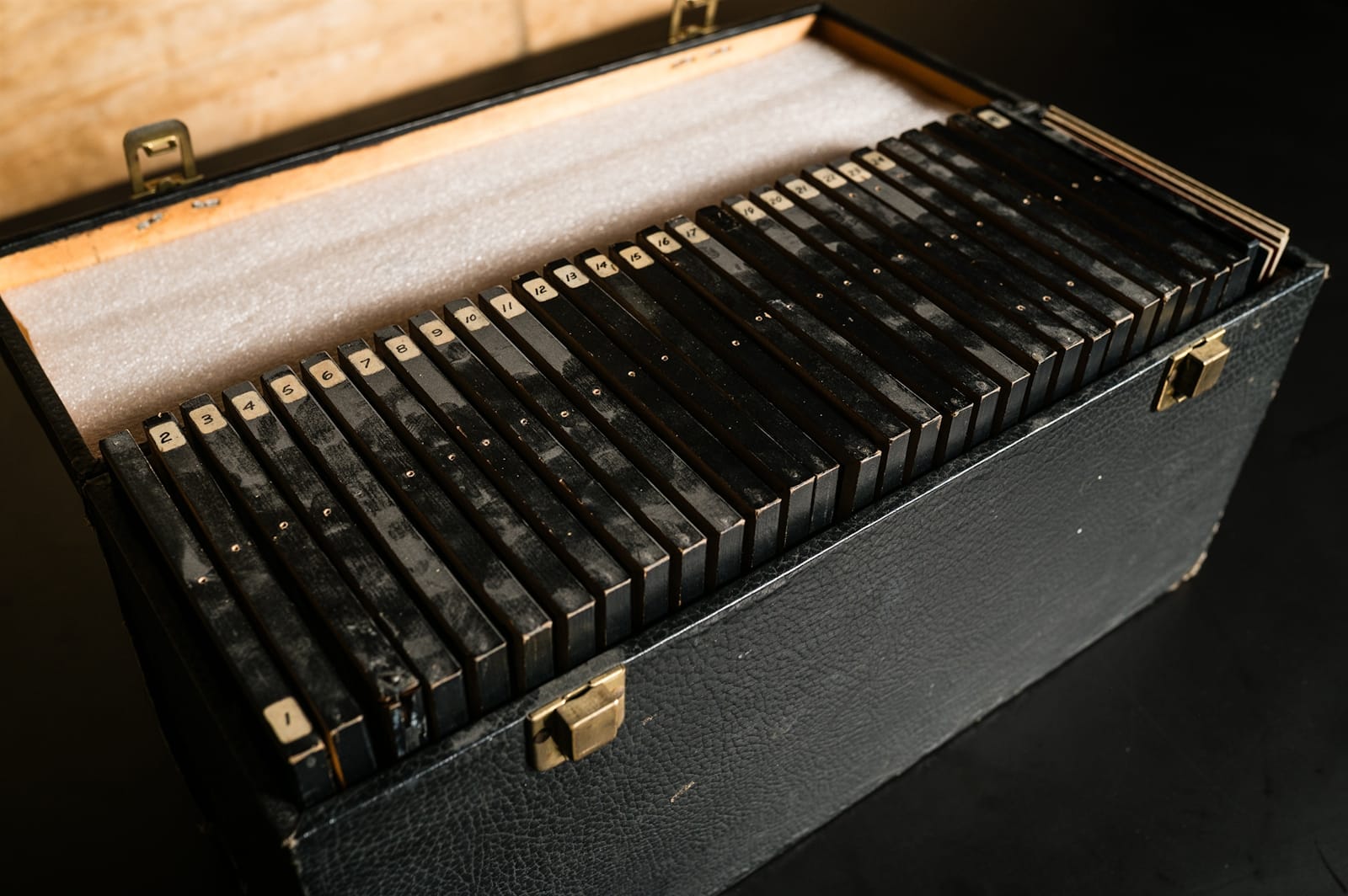 An open box with the edges of tightly packed black picture frames visible.