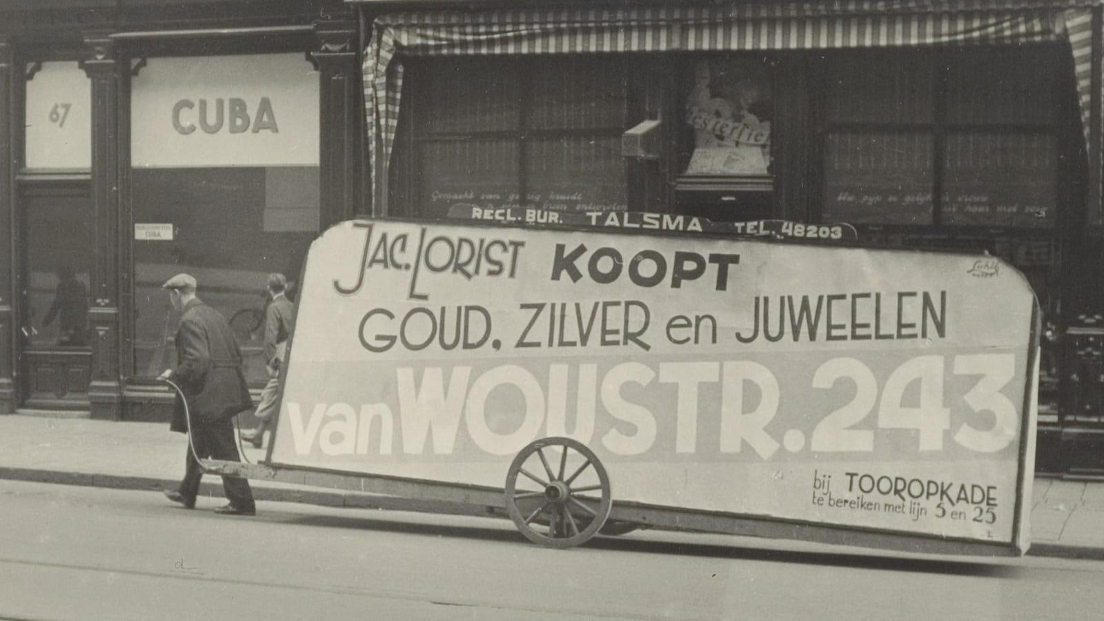 Man pulling a cart that has a billboard-sized sign mounted onto it. Lettering on the sign includes "Jac. Lorist, Koopt, Goud, Zilver en Jeweelen, van Woustr. 243".